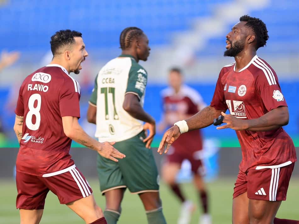 Flávio Medeiros do Al Faisaly, nº8, celebra com colegas durante partida de futebol.