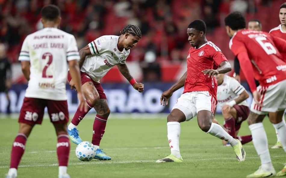 Jogo entre Fluminense e Internacional, jogadores disputam a bola em campo.