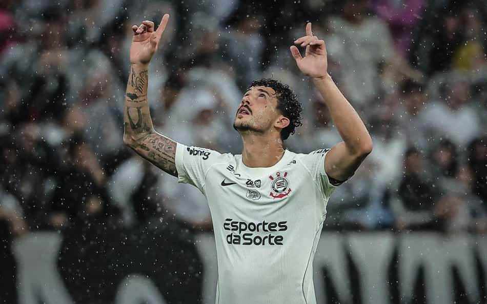 Gustavo Henrique celebra em campo sob chuva, braços erguidos, camisa branca.