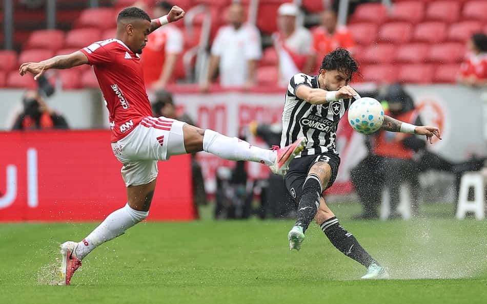 Jogador do Internacional (vermelho) disputa bola com Botafogo (listras pretas e brancas) no jogo Internacional 3 x 0 Botafogo.