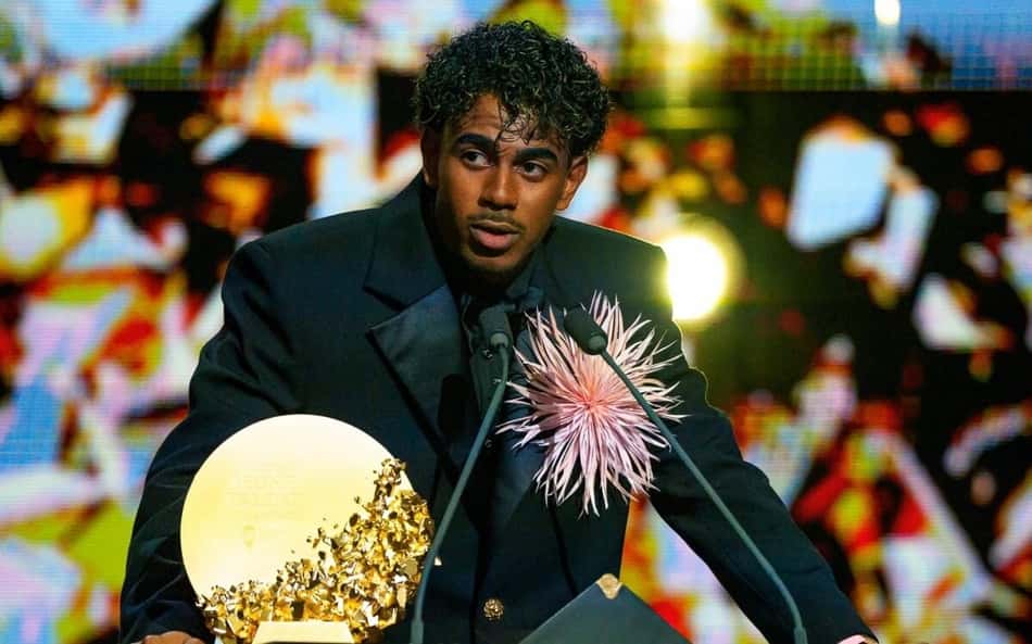 Lamine Yamal no palco do Ballon d'Or, ao lado do troféu dourado.