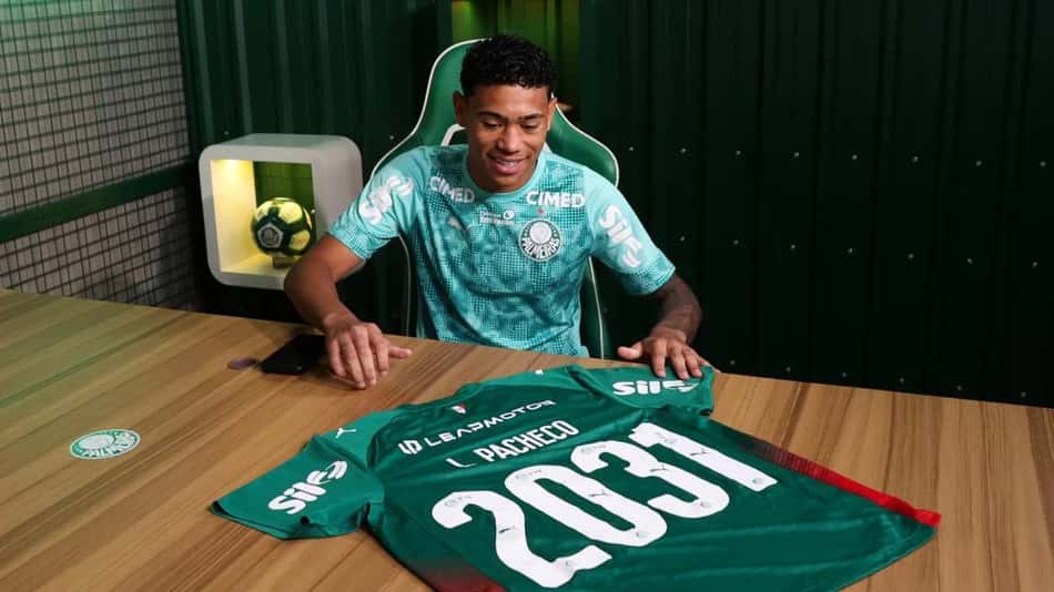 Luis Pacheco renova contrato com o Palmeiras, diante da camisa verde com o nome L. Pacheco sobre a mesa.