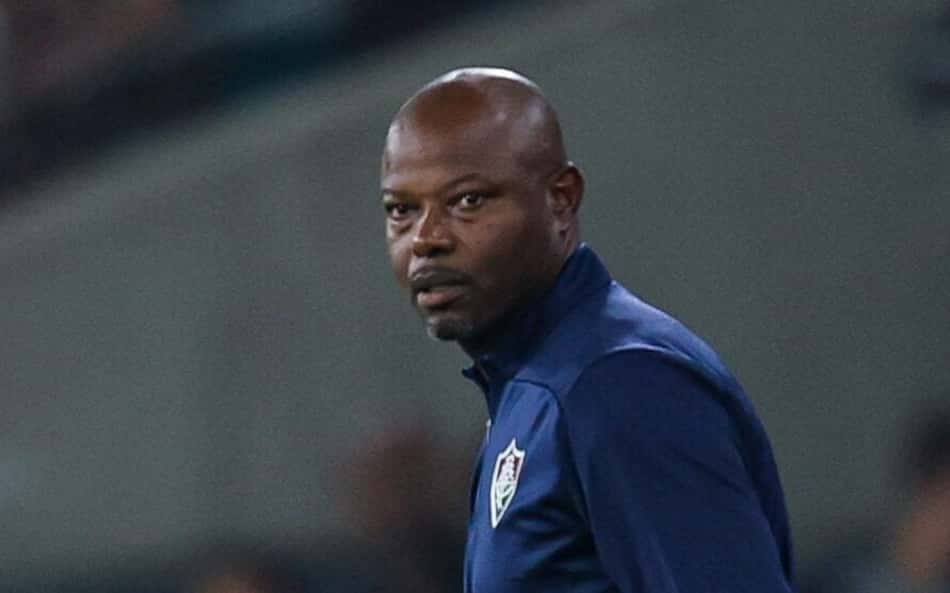 Marcão do Flu segura a bola em campo, ao lado de outro técnico.