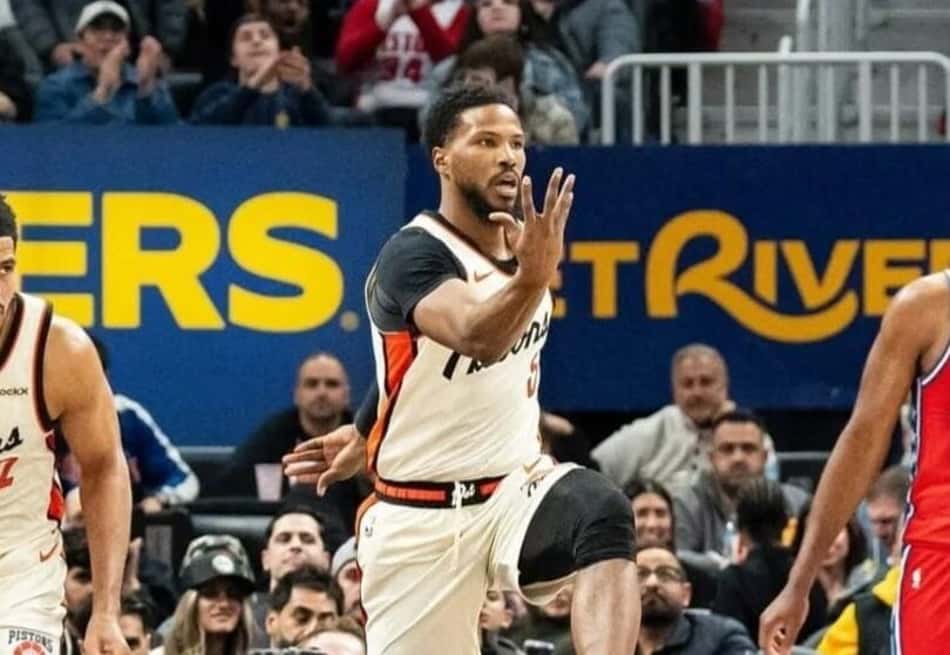 Malik Beasley em ação durante partida de basquete da NBA, com torcedores ao fundo.