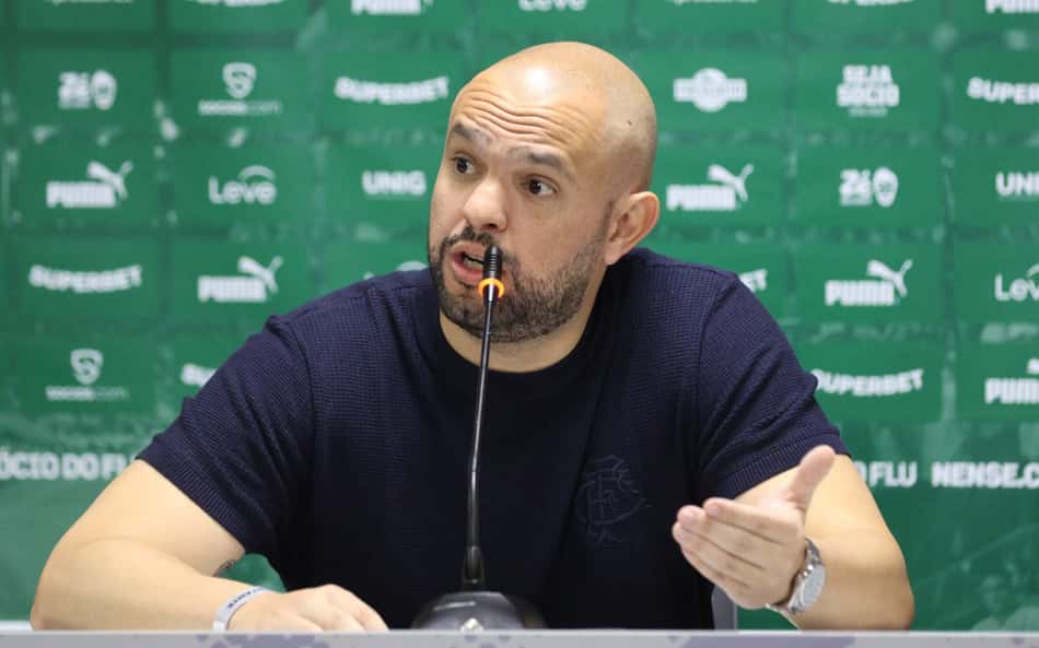 Mattheus Montenegro, presidente do Fluminense, em coletiva de imprensa com microfone à mesa.