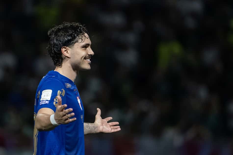 Mauricio, jogador de futebol, celebra em campo com os braços abertos, camisa azul.