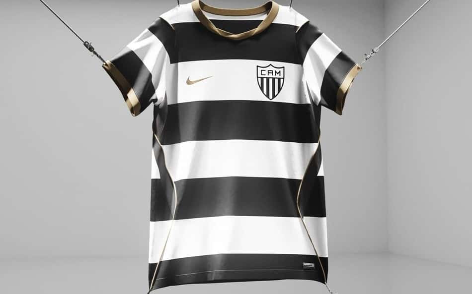 Camiseta do Atlético Mineiro da Nike, listras pretas e brancas com detalhes dourados, suspensa em estúdio.