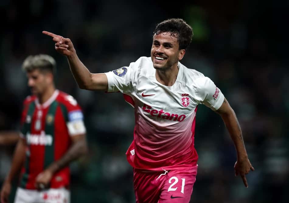 Jogador do Sporting celebra durante a partida, sorrindo e apontando.