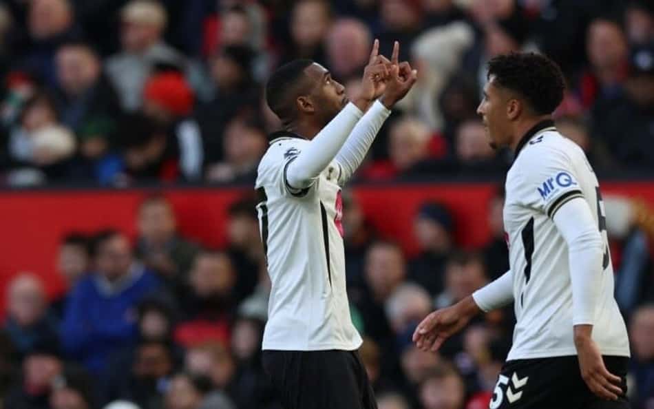 Três jogadores de Bournemouth e Manchester United celebram em campo, com torcida ao fundo.