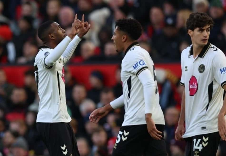 Rayan celebra gol pelo Bournemouth durante a partida, acompanhado por colegas, com torcida ao fundo.