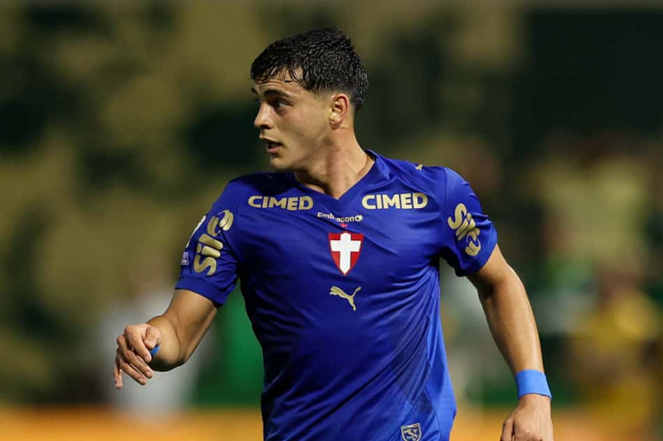 Sosa, jogador em uniforme azul, correndo com a bola durante partida de futebol.