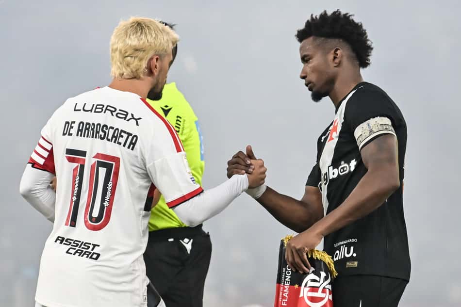 De Arrascaeta (Flamengo) aperta a mão de jogador do Vasco no Vasco x Flamengo, árbitro ao fundo.