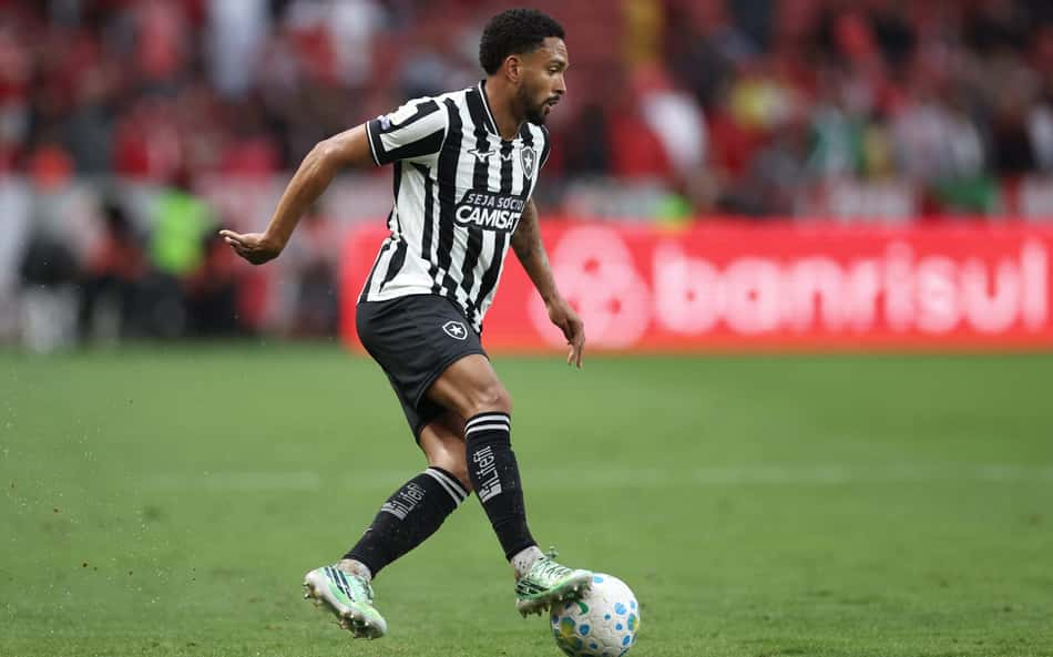 Vitinho, jogador do Botafogo, em ação durante a partida, conduzindo a bola.