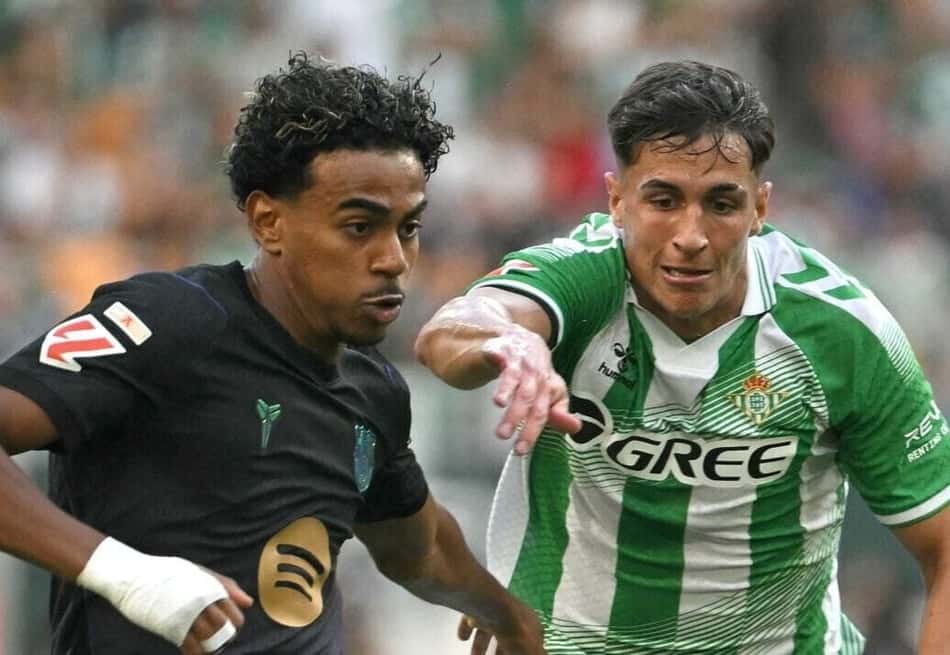 Yamal em duelo com jogador de uniforme verde e branco durante partida de futebol.