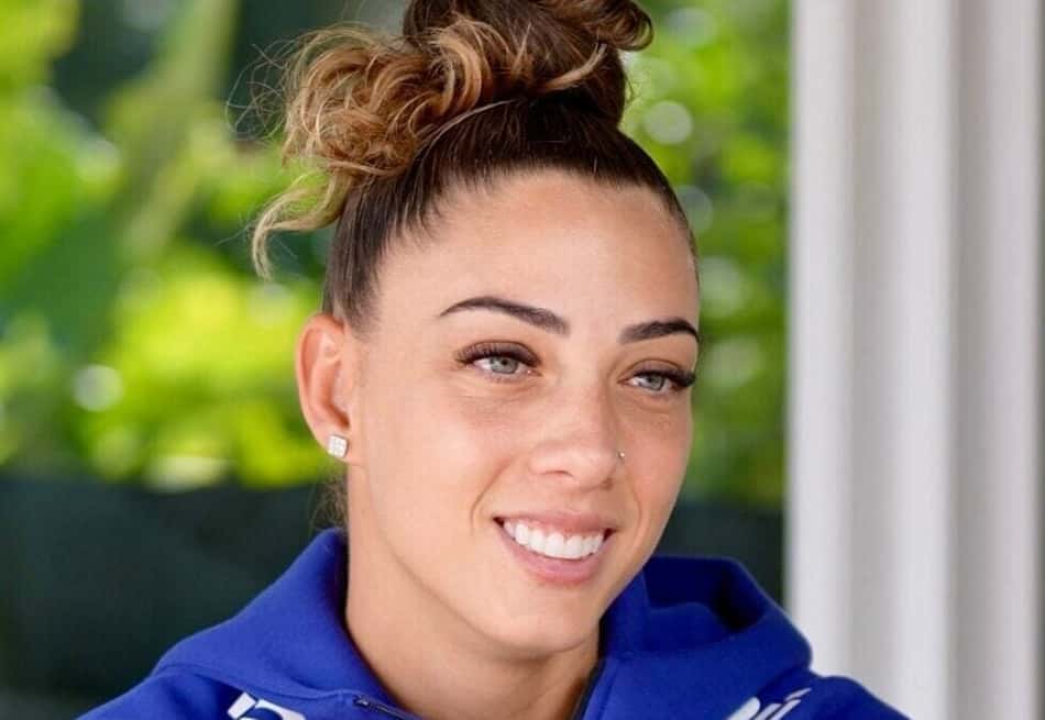 Yanne, de cabelo preso, sorridente com casaco da Seleção Brasileira