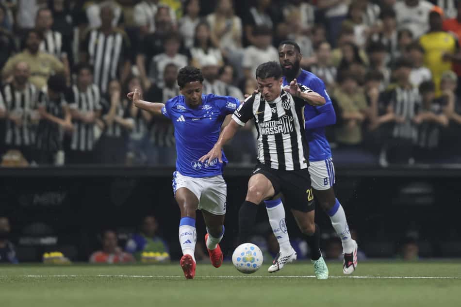 Zé Lucas e Alan Franco disputam a bola em partida de futebol, com adversários de camisa azul.