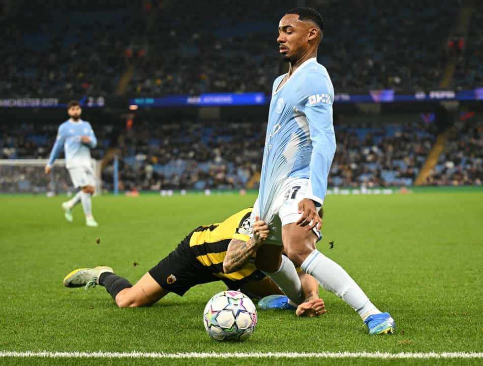 O zagueiro grego do AEK, número 12, Lázaro Rota, puxa a camisa do meio-campista brasileiro do Manchester City, número 37, Allan Elias, durante a partida da Liga dos Campeões da UEFA entre Manchester City e AEK Atenas, no Etihad Stadium, em Manchester, noroeste da Inglaterra, em 20 de outubro de 2026. (Foto: Oli Scarff / AFP)