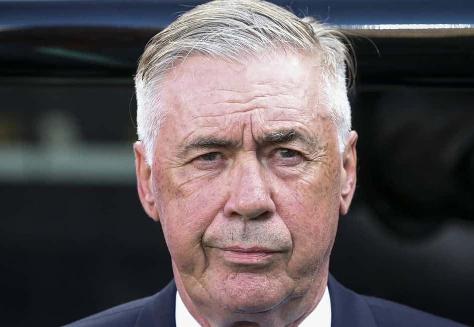 Carlo Ancelotti, de terno, olhando para frente com expressão séria