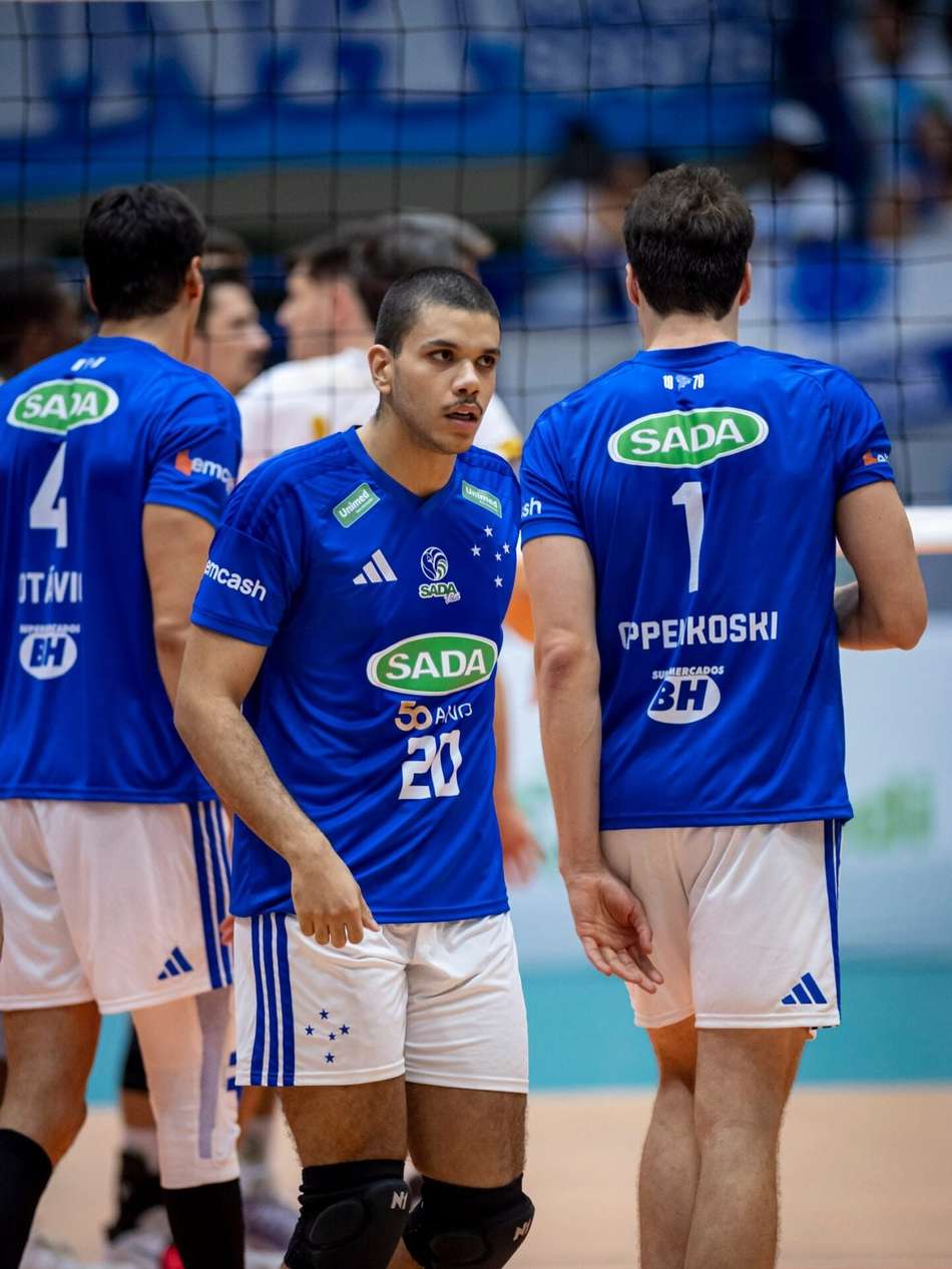 Três jogadores do Minas Vôlei, uniformes azuis com patrocínio SADA, na quadra de vôlei