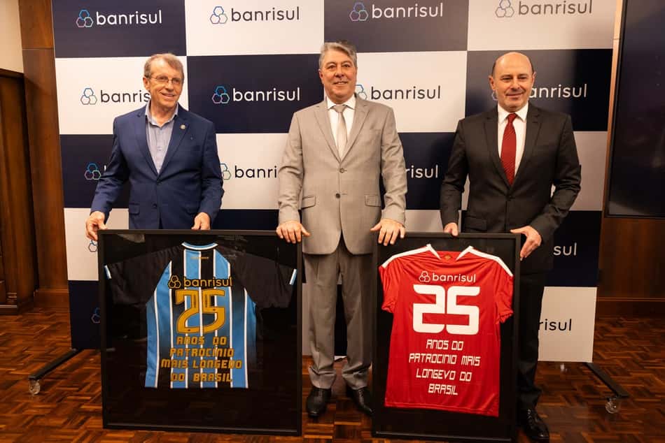 Executivos posam com camisas do Grêmio e do Internacional, celebração de 25 anos de patrocínio Banrisul no Brasileirão.