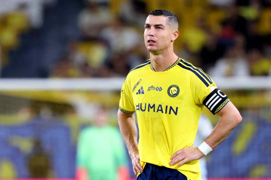 Jogador de futebol vestindo camisa amarela do Al Nassr, com braçadeira de capitão, em campo.