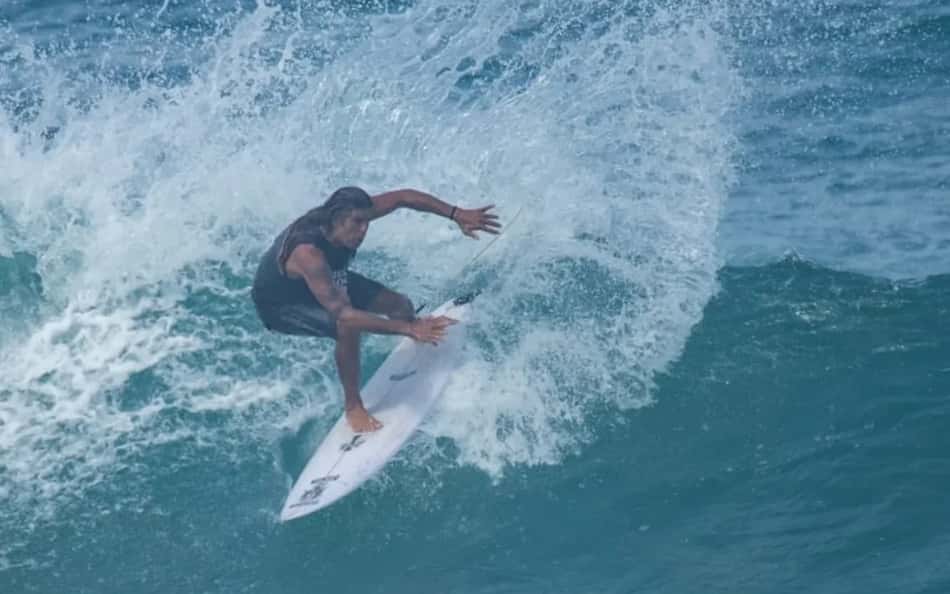 Dadá Figueiredo surfa onda azul, spray de água ao redor da prancha.