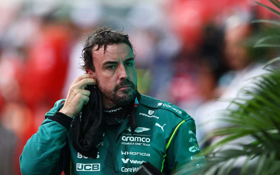 Fernando Alonso no GP dos EUA de Fórmula 1, com macacão da Aston Martin, retirando o rádio.