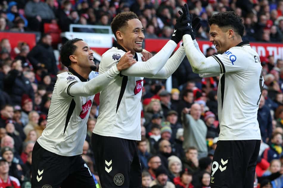 Três jogadores do AFC Bournemouth celebram o gol, trocando cumprimentos entre si diante da torcida.