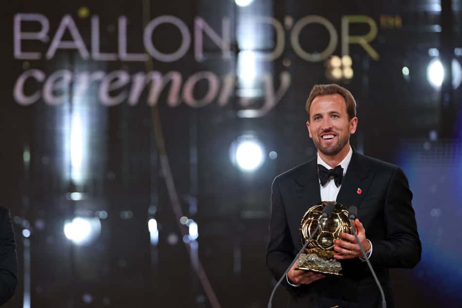 Homem de terno preto no palco segurando o troféu Ballon d'Or na cerimônia.