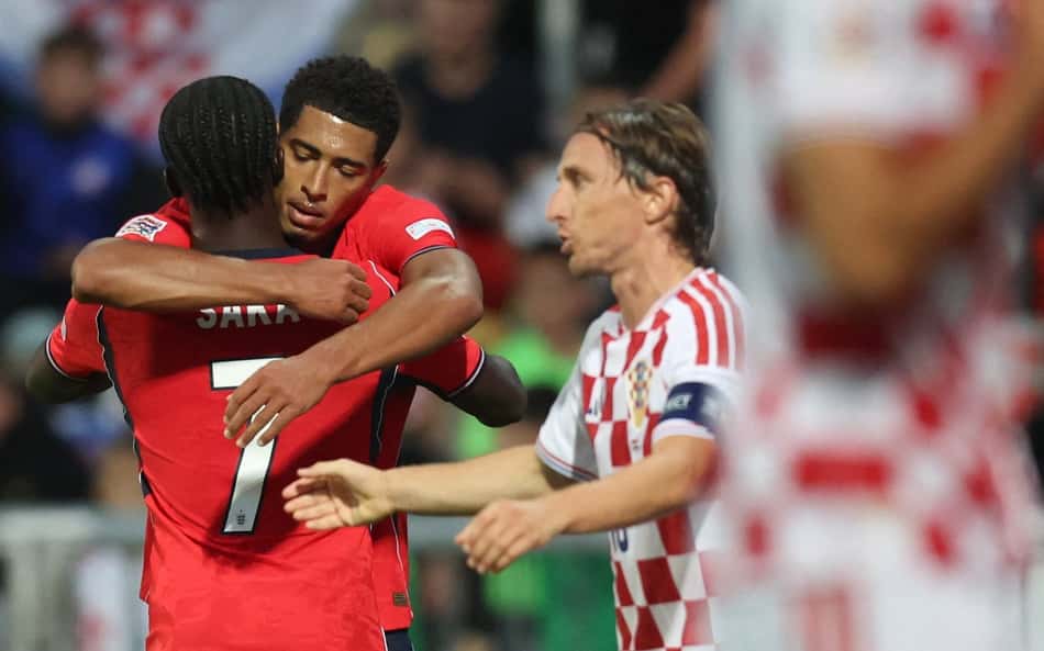O meio-campista inglês nº 10 Jude Bellingham comemora com o companheiro de equipe, o atacante inglês nº 7 Bukayo Saka, após marcar o quarto gol da Inglaterra, enquanto o meio-campista croata nº 10 Luka Modric (à direita) reage durante a partida de futebol da Liga das Nações da UEFA, Grupo 3, Liga A, entre Croácia e Inglaterra, no Estádio HNK Rijeka, em Rijeka, Croácia, em 3 de outubro de 2026 (Foto: Marko Perkov / AFP)