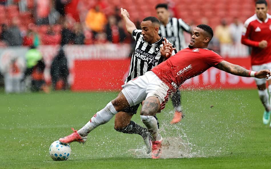 Internacional x Botafogo no Brasileirão, duelando pela bola entre camisa vermelha e listras preto e branco.