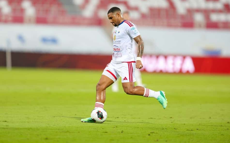 Leandrinho em campo, jogador de uniforme branco com detalhes vermelhos, driblando a bola.
