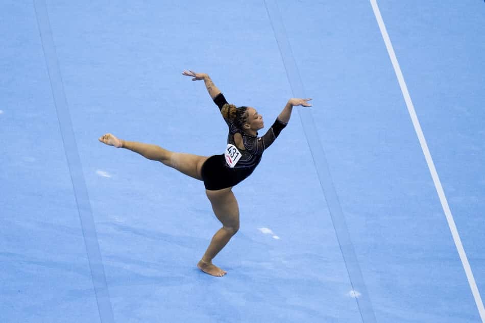 Lorrane Oliveira em salto de ginástica artística na competição mundial, sobre tapete azul.