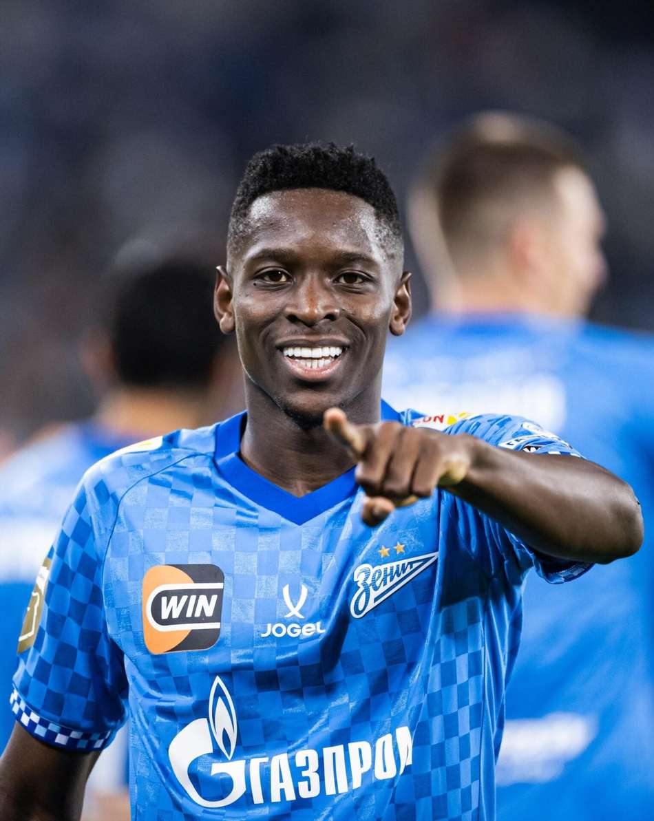 Luiz Henrique, jogador do Zenit, em uniforme azul, sorrindo e apontando para a câmera.