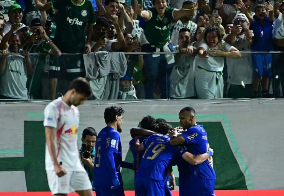 Palmeiras celebra gol com jogadores se abraçando, torcedores ao fundo no estádio.