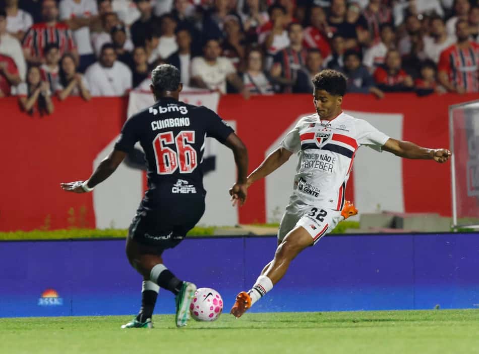 Jogador do São Paulo disputa a bola contra o Vasco da Gama em partida de futebol.