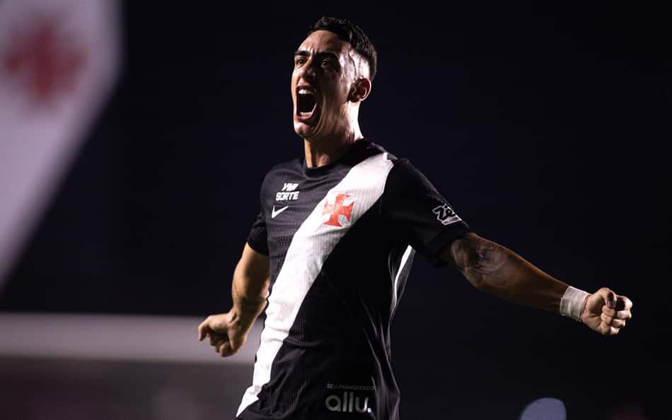Jogador de futebol em camisa preta com faixa diagonal branca celebra, com o braço direito estendido.