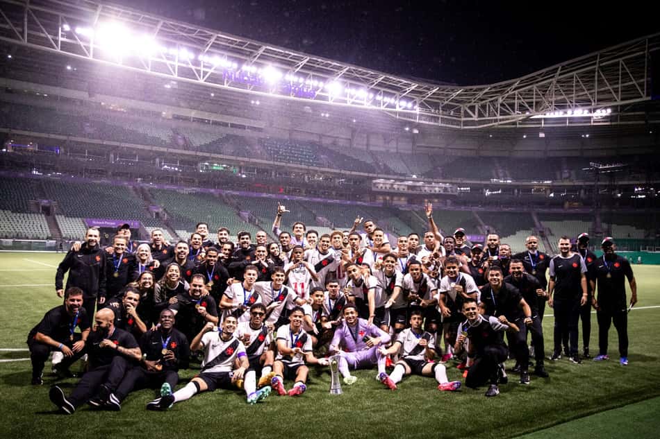 Vasco Sub-20 e comissão técnica posam com troféu no campo, em estádio lotado.