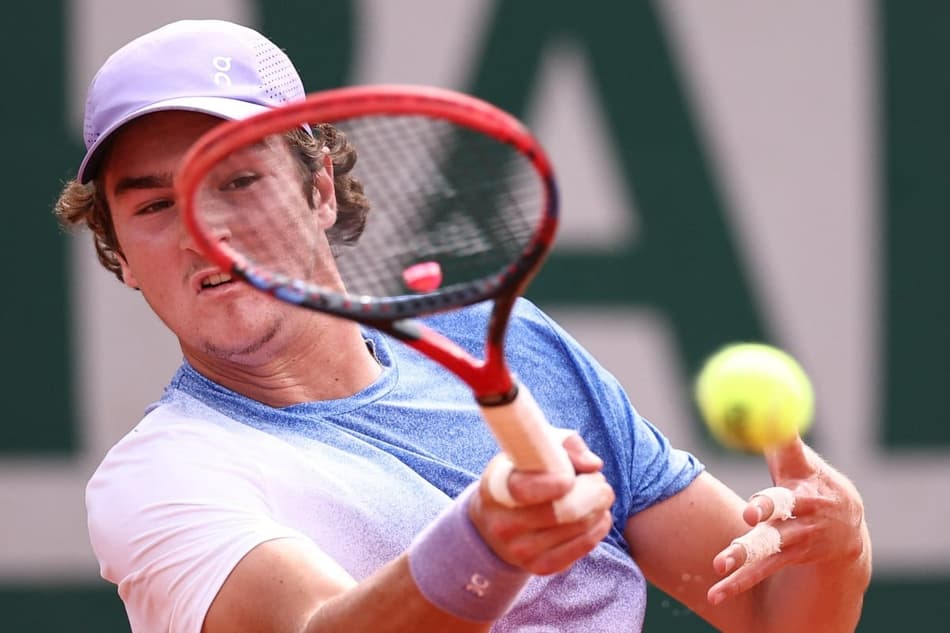 João Fonseca bate de direita na partida contra o francês Pierre-Hugues Herbert em Roland Garros (Photo by Anne-Christine POUJOULAT / AFP)