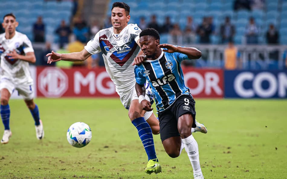 Amuzu e Arce em disputa de bola no jogo entre Grêmio e Godoy Cruz. (Foto: Maxi Franzoi/AGIF)