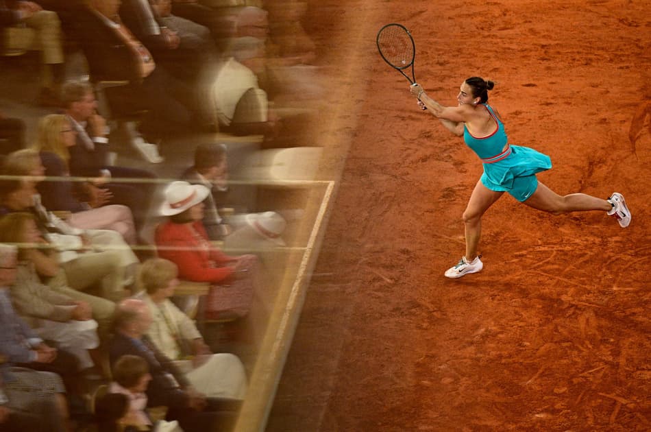 Spectators are reflected in a glass as Belarus' Aryna Sabalenka plays a backhand return to Poland's Iga Swiatek during their women's singles semi-final match on day 12 of the French Open tennis tournament on Court Philippe-Chatrier at the Roland-Garros Complex in Paris on June 5, 2025. (Photo by JULIEN DE ROSA / AFP)
