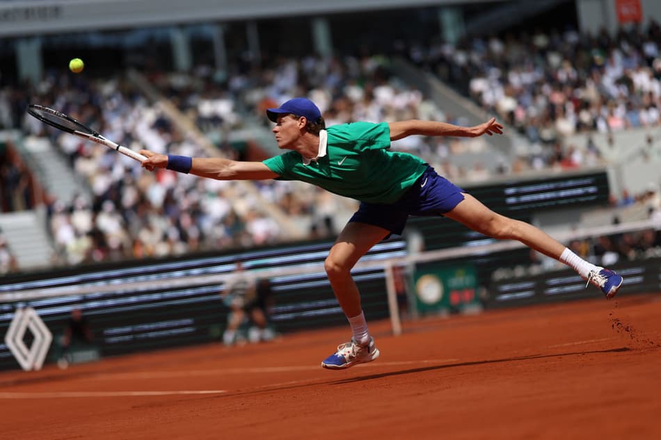 O italiano Jannik Sinner se estica para devolver a bola para o espanhol Carlos Alcaraz na final de Roland Garros (Foto: Alain JOCARD / AFP)