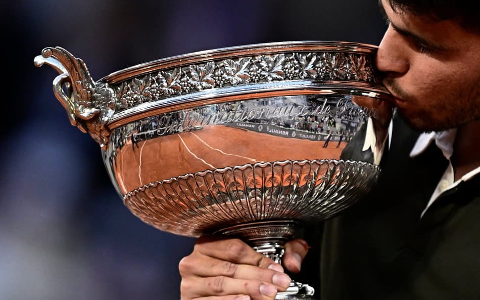 O espanhol Carlos Alcaraz beija o troféu de Roland Garros (Foto: JULIEN DE ROSA / AFP)
