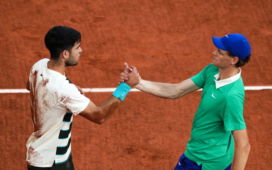 O espanhol Carlos Alcaraz e o italiano Jannik Sinner se cumprimentam após a épica final de Roland Garros (Foto: Dimitar DILKOFF / AFP)