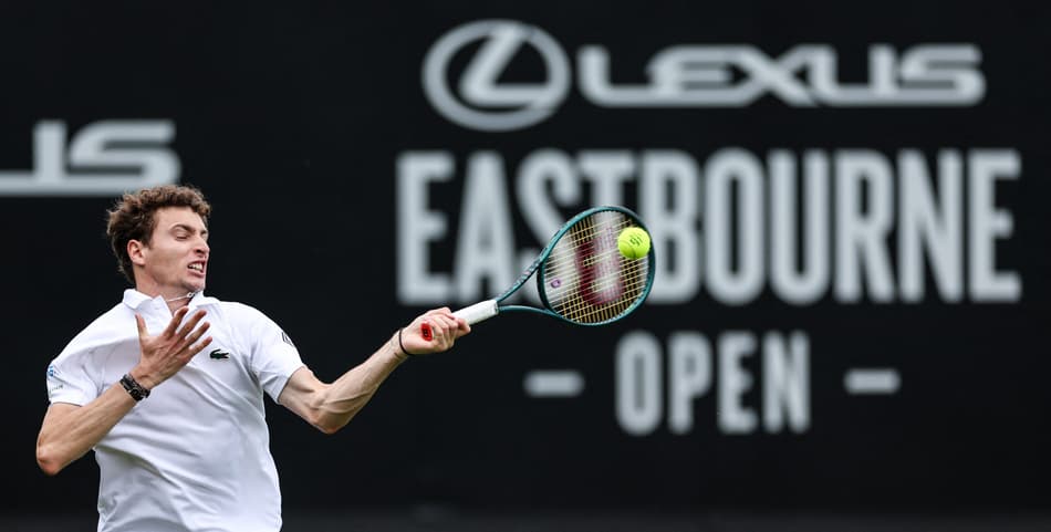O francês Ugo Humbert devolve a bola contra o italiano Lorenzo Sonego em Eastbourne (Foto: Adrian Dennis / AFP)