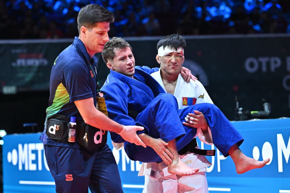 Brasileiro Michel Augusto é carregado pelo adversário Yolk Kazirbyek, da Mongólia, após luta pela categoria -60kg masculina (foto: Attila KISBENEDEK / AFP)