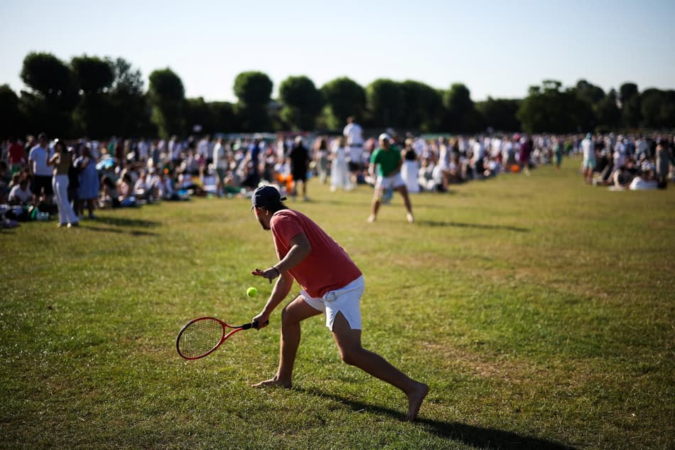 Torcedores jogam tênis enquanto fazem fila para conseguir ingressos no primeiro dia de Wimbledon (foto: HENRY NICHOLLS / AFP)