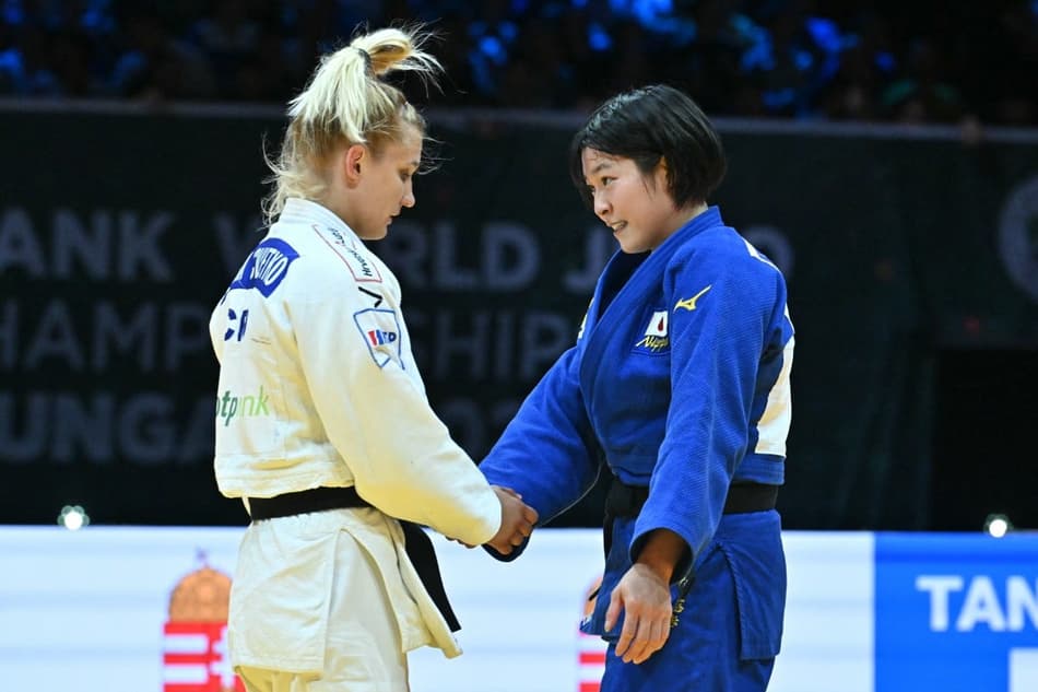 A japonesa Shiho Tanaka (azul) cumprimenta a croata Lara Cvjetko após vencer a luta da final feminina (Photo by Attila KISBENEDEK / AFP)