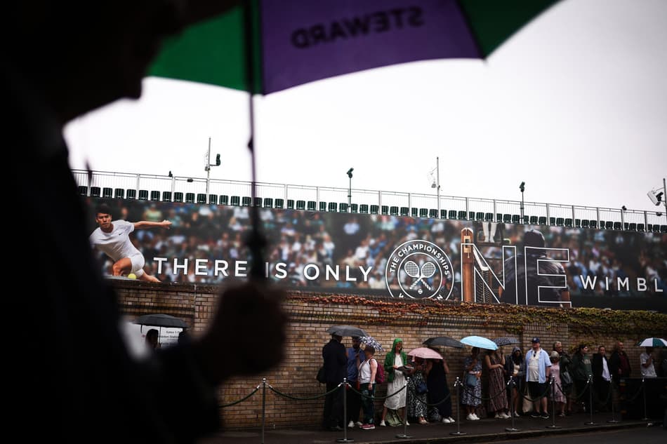 Torcedores se protegem com guarda-chuva em Wimbledon (Foto: HENRY NICHOLLS / AFP)