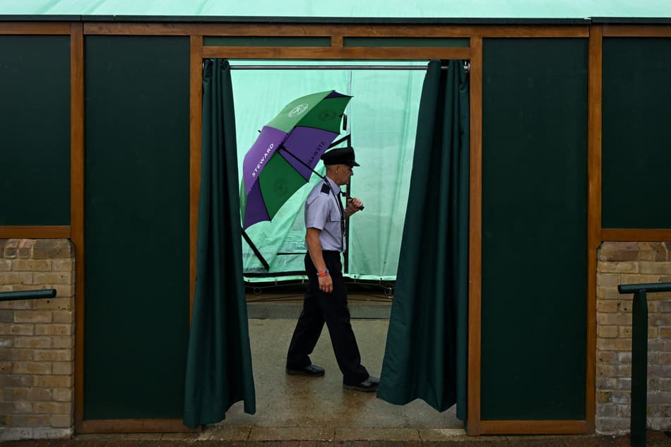 Segurança também se protege da chuva no The All England Lawn Tennis and Croquet Club em Wimbledon (Foto: Kirill KUDRYAVTSEV / AFP)